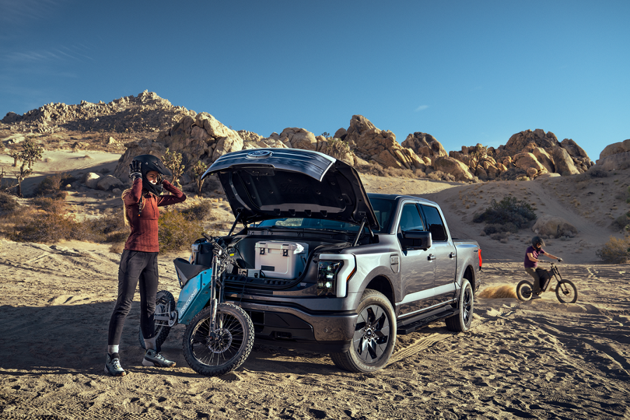 A person charges an e-bike from a power port on a Ford F 1 50 Lightning